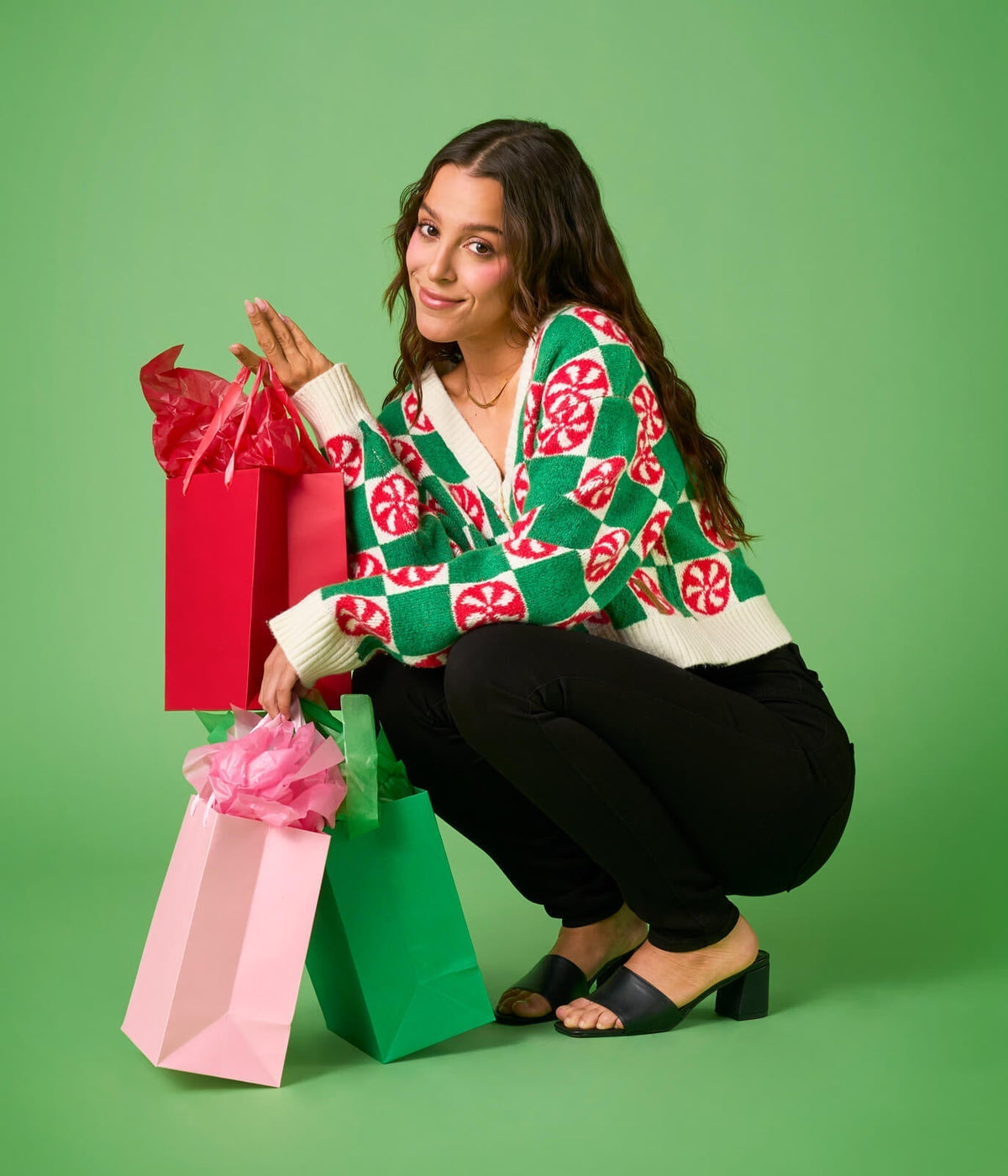 Woman in a colorful sweater with shopping bags on a green background