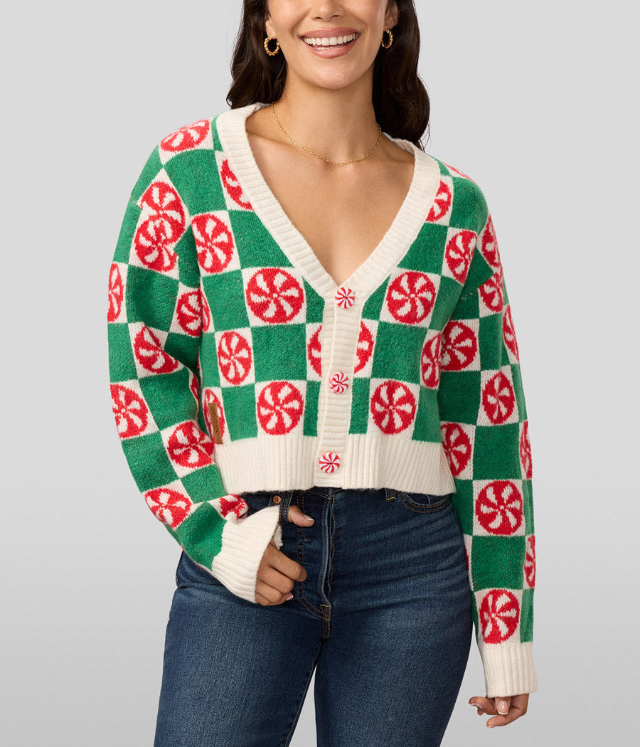 Woman wearing a green and red patterned sweater with a plain background